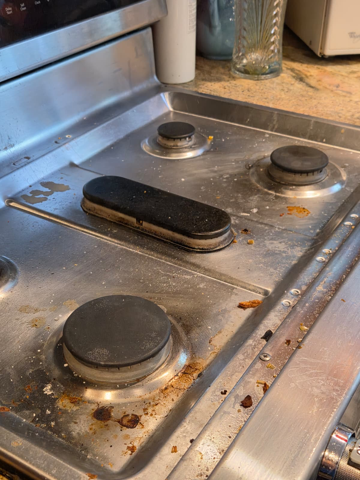 Before cleaning: visible food residue and grime on a stainless steel stovetop